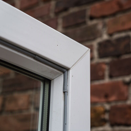 Detailopname van een stijlvolle donkergrijze kunststof deurpost met geïntegreerd beslag tegen een schoon metselwerk muur in Heemskerk